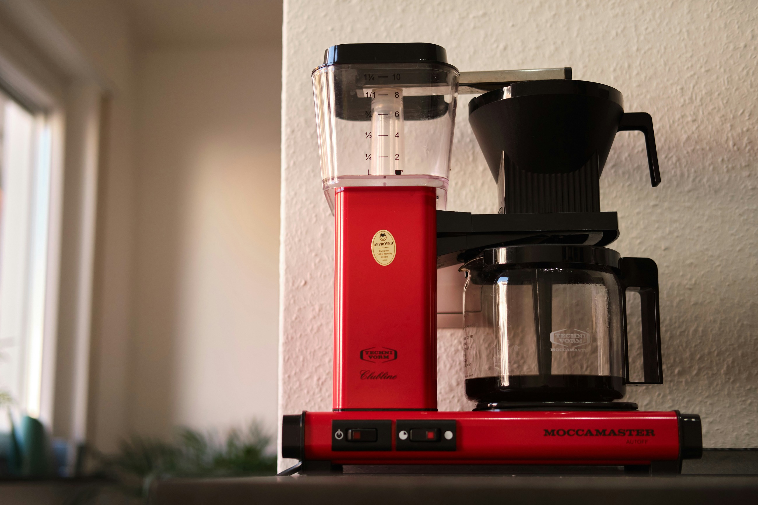 A coffee maker sits on a kitchen counter beside a window